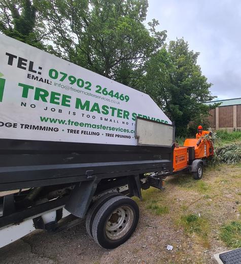 A large white trailer with tree surgery contact information on the side